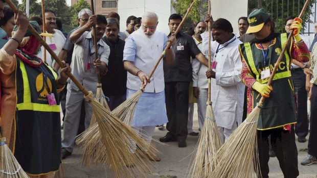 Indian Prime Minister Narendra Modi, centre, sweeps a road with civic workers in New Delhi. 