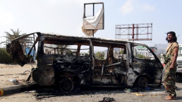 Fighting continues: A man stands by the wreckage of a van hit by an air strike in Yemen's southern port city of Aden.