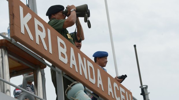 Indonesian Military chief General Moeldoko surveys the area with binoculars as navy divers take part in an operation to raise the tail of AirAsia QZ8501 from the Java Sea.