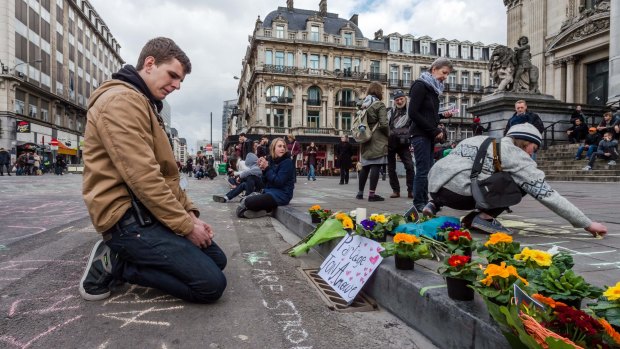 A man looks at flowers and messages outside the stock exchange in Brussels after the attacks.