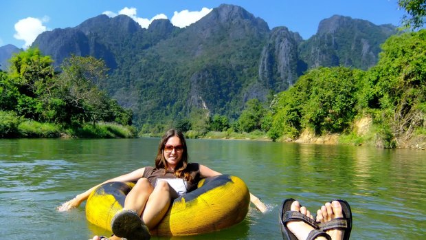 A couple drift down Nam Song River in a tube surrounded by karst scenery in Vang Vieng, Laos. 
