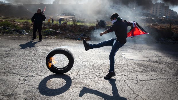 A Palestinian protester kicks a tire following protests against US President Donald Trump's decision to recognise Jerusalem as the capital of Israel.