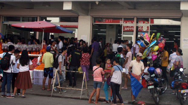 Residents crowd the entrance of a grocery store in Tacloban City, ahead of the landfall of Typhoon Hagupit. 