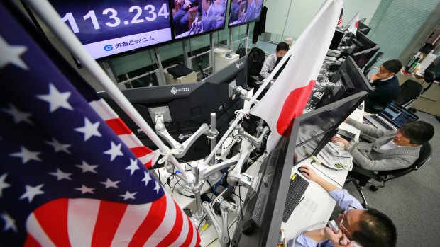 Money traders watch the day's exchange rate at a foreign exchange brokerage in Tokyo.