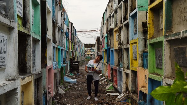 Elena de Chavez 61 holding a photo of her transgender son Alvin Ronald de Chavez also known as 'Heart', searches for his tomb at the Navotos Catholic Cemetery in Manila.