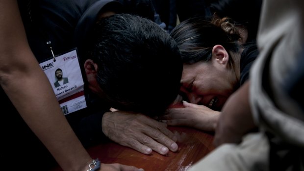 The family of murdered photojournalist Ruben Espinosa cry on his coffin during his funeral service.