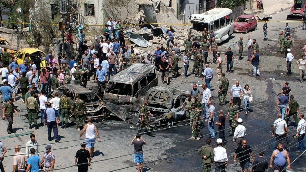 Syrians gather at the site of a car bombing in a square at the port city of Latakia, Syria, on Wednesday. The violence is one of the drivers for the exodus of Syrians.
