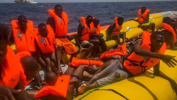 Migrants wait to be rescued by aid workers next to the dead bodies of other migrants in the Mediterranean Sea.