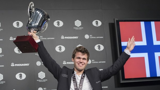 Carlsen holds up his championship cup. 