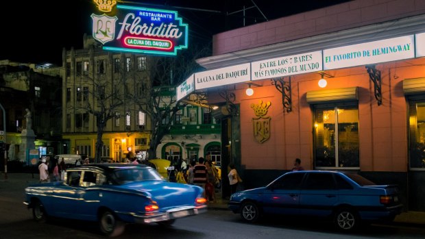 Vintage car passing by at night next to the famous Floridita bar in old Havana.