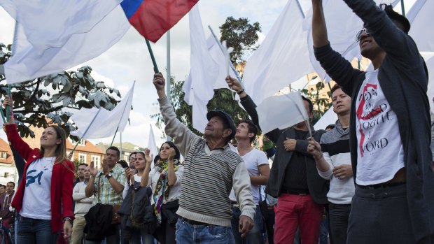 People wave flags after learning about the rejection of a peace deal with the FARC following a plebiscite in Bogota.