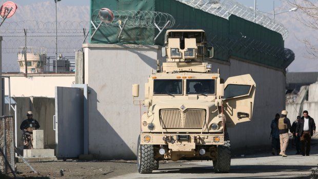 A US military vehicle on Tuesday blocks a road to a logistics company near the site of a deadly suicide attack, claimed by the Taliban, that killed several people and wounded at least 36 civilians, including nine women.