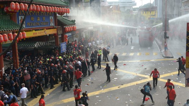Riot police fire a water cannon at 'red-shirt' protesters in Kuala Lumpur's Chinatown neighbourhood.