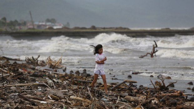 A girl walks along the shore as strong waves from Typhoon Hagupit hit Atimonan in the eastern Philippines.