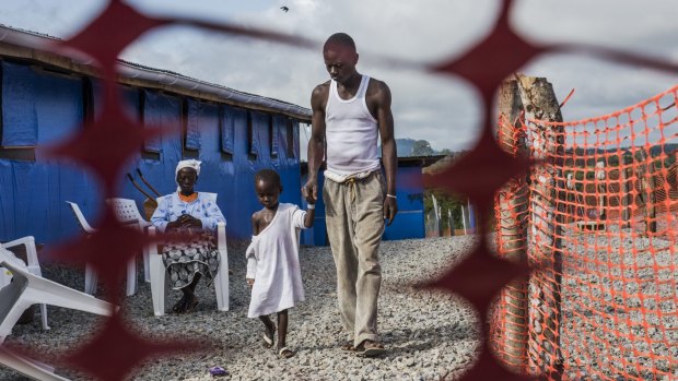 George Beyan, an Ebola survivor, with his five-year-old son Williams, who had the virus, at the Bong County Ebola Treatment Centre in Suakoko, Liberia on October 19, 2014. 