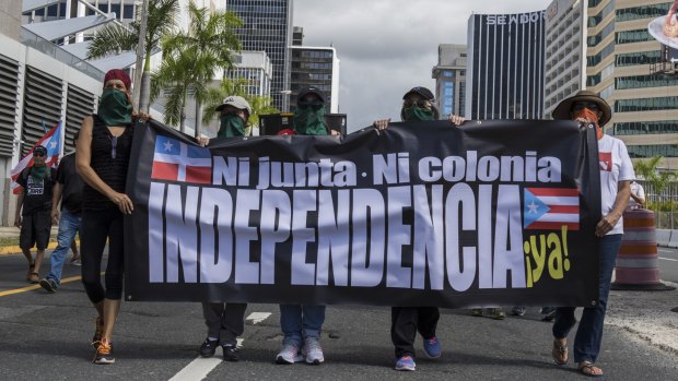 Protesters hold a banner saying "no junta, no colony, independence now" during Puerto Rico's status referendum on Sunday.