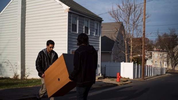 Amer al-Fayadh, a senior case manager with the Church World Service, and Orion Hernandez carry a dresser into a home being prepared for a Syrian refugee family in Lancaster.