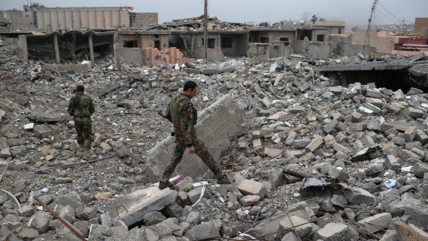 Peshmerga soldiers search for weapons in the rubble of an airstrike last November in Sinjar, Iraq. 