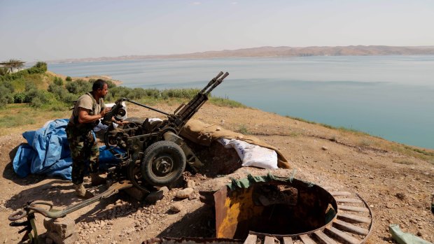 A Kurdish peshmerga prepares his weapon at his combat position on the shores of the Mosul dam.