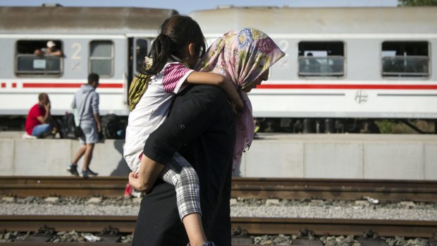 A woman carries a child at a train station near the Hungarian border in Croatia. 