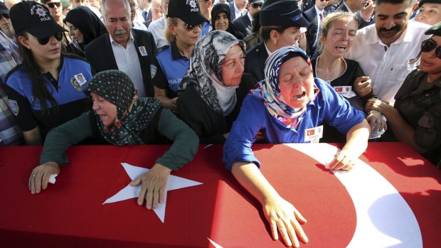 Hulya Aydin (right) the mother of Turkish police officer Sahin Polat Aydin, one of the four officers killed on Monday, cries over his coffin.