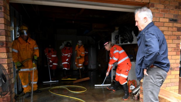 Prime Minister Malcolm Turnbull speaks with emergency services personnel as he tours a flood-damaged street in Eagleby.