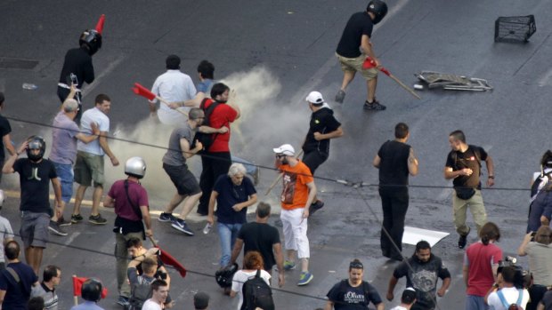 Riot police throw tear gas as demonstrators run.