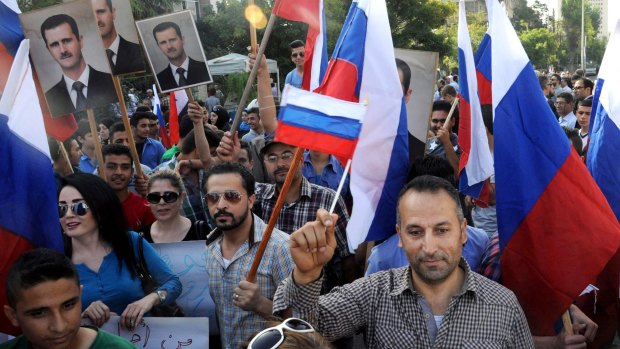 Syrians hold photos of President Bashar al-Assad and Russian flags during a protest to thank Moscow for its intervention in Syria.