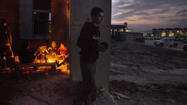 Sixteen-year-old Sabah dropped out of school to work in the Summel market (right). Workers warm themselves on a fire before starting at 5am.