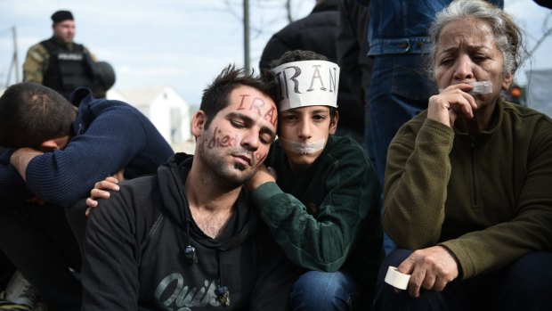 Exhausted migrants sit in no-man's land demanding to be allowed to pass the Greek-Macedonian border on Tuesday.