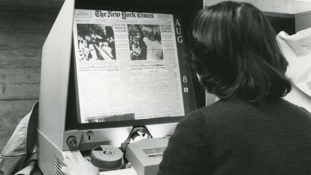 Reading an archived copy of The New York Times on a microfilm machine.