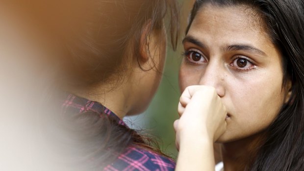 A family member comforts the daughter (right) of Senior Superintendent of Police Laxman Neupane, who was killed in Monday's protest in Kathmandu.