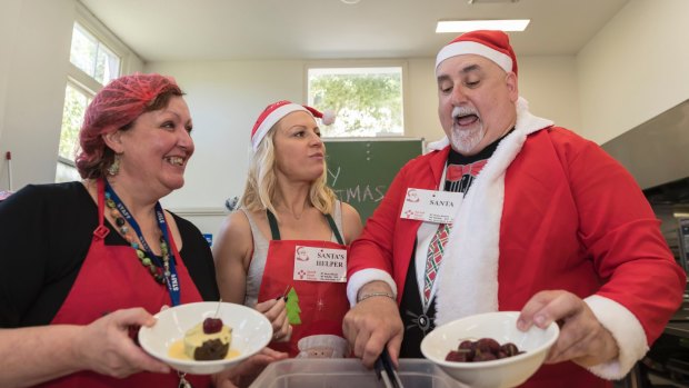 Volunteers (from left) Robyn Findlay, Megan Reilly and Kevin Rooney dish up Christmas cheer at the Sacred Heart Mission.