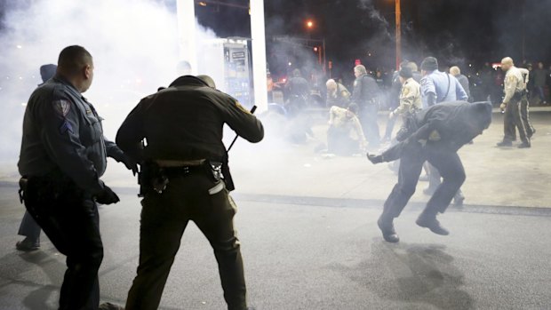 Police face an angry crowd at the scene of the shooting.