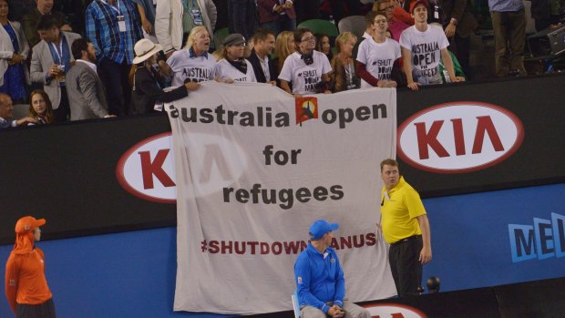 Protesters unfurl a banner during the men's final, drawing attention to the plight of refugees on Manus Island. 