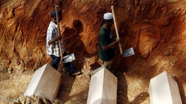 Workmen walk among coffins in a mass grave of unidentified Rohingya remains found at a traffickers camp in Wang Kelian, at a cemetery near Alor Setar, Malaysia, in June.