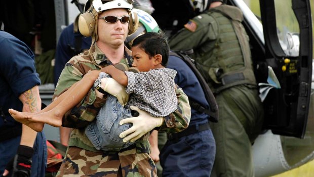 Lt. Shawn Harris carries an injured boy to a triage site setup by various relief groups on the Sultan Iskandar Muda Air Force Base in Aceh, Sumatra January 6, 2005.
