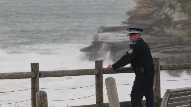Police watch on as emergency services search for missing swimmer Endicott Ackerman, 20, south of Bondi Beach.