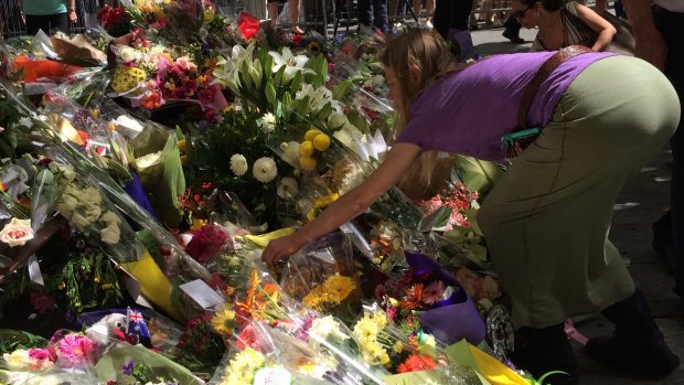 Joanne Proctor spreads sage ashes at the memorial outside the Lindt cafe.
