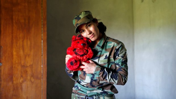 Asema Dahir, 21, poses with a teddy bear in a bedroom at a site near the frontline of the fight against Islamic State.