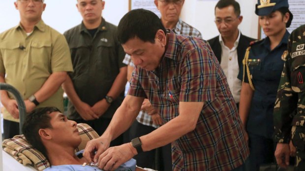 Philippine President Rodrigo Duterte pins a medal on a soldier wounded in Monday's gunbattle with Muslim Abu Sayyaf militants.