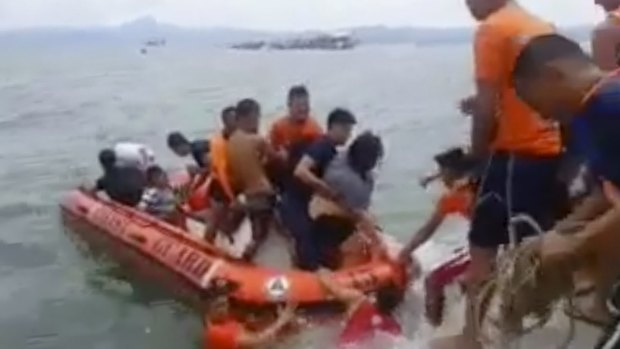 Rescuers help passengers from a capsized ferry pictured in the distance. 