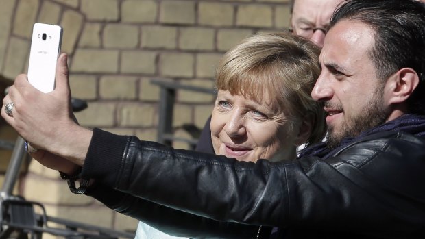 German Chancellor Angela Merkel, left, agrees to a selfie during her visit to a migrant registration centre in Berlin last month.
