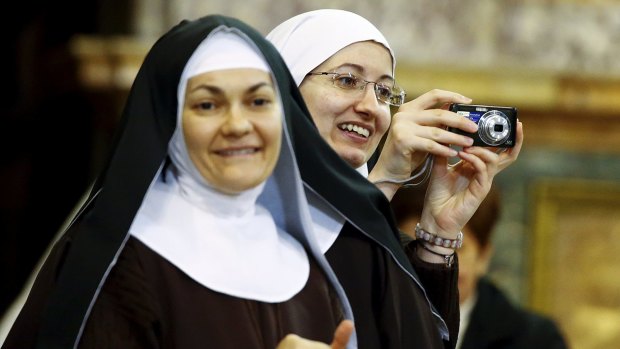 A nun takes a picture as Pope Francis arrives at the Naples' Duomo.
