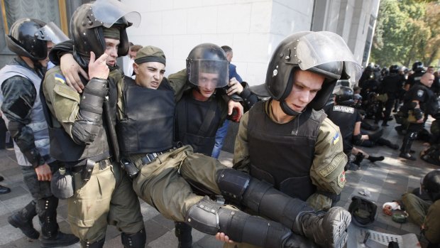 Police officers give aid to a colleague after a grenade blast during protests in Kiev.