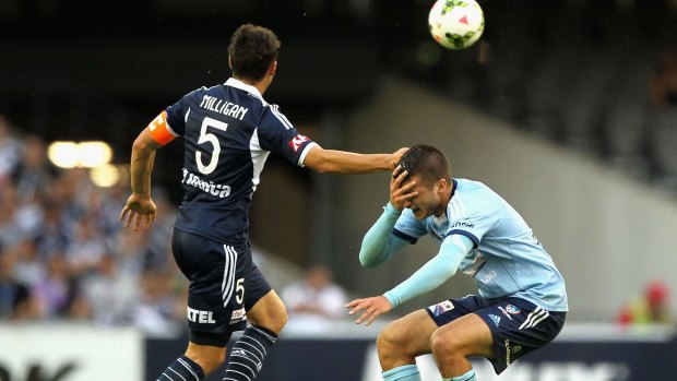 Victory's Mark Milligan and Sydney's Terry Antonis collide during the A-League match on Saturday.