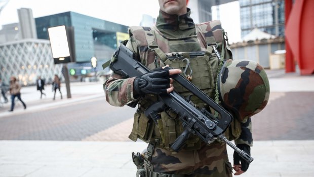 An armed member of the French armed forces stands guard as commuters went back to work at La Defense business district in Paris on Monday.