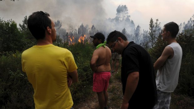 Residents watch on as Portuguese firefighters working to stop a forest fire from reaching the village of Figueiro dos Vinhos.