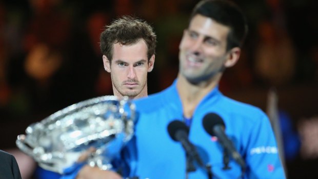 Winner takes all: Andy Murray looks on as Novak Djokovic holds the men's singles trophy.