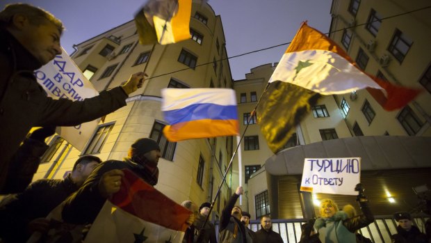 Protesters wave Russian and Syrian flags and signs reading 'Turkey to account!' outside the Turkish embassy in Moscow on Tuesday.